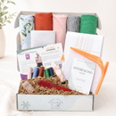 Box of sewing supplies including fabric, threads, and guides on a white background