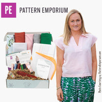 Woman standing next to a box from Pattern Emporium with fabric and sewing supplies.