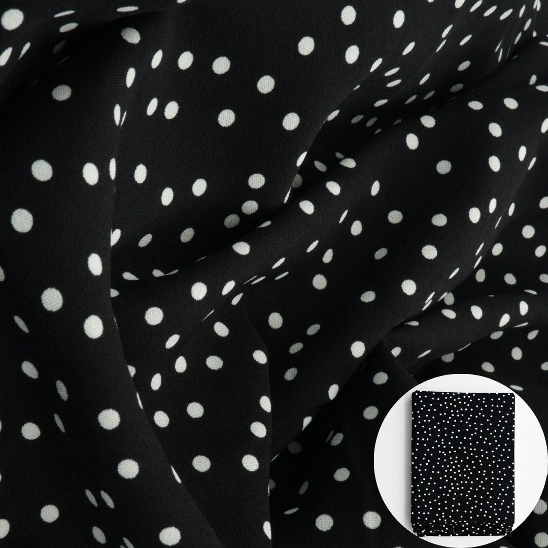 Black fabric with a white polka dot pattern, shown draped with a small circular inset of folded fabric.