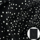 Black fabric with a white polka dot pattern, shown draped with a small circular inset of folded fabric.