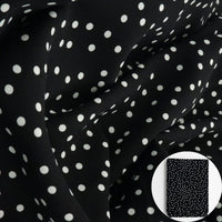 Black fabric with a white polka dot pattern, shown draped with a small circular inset of folded fabric.