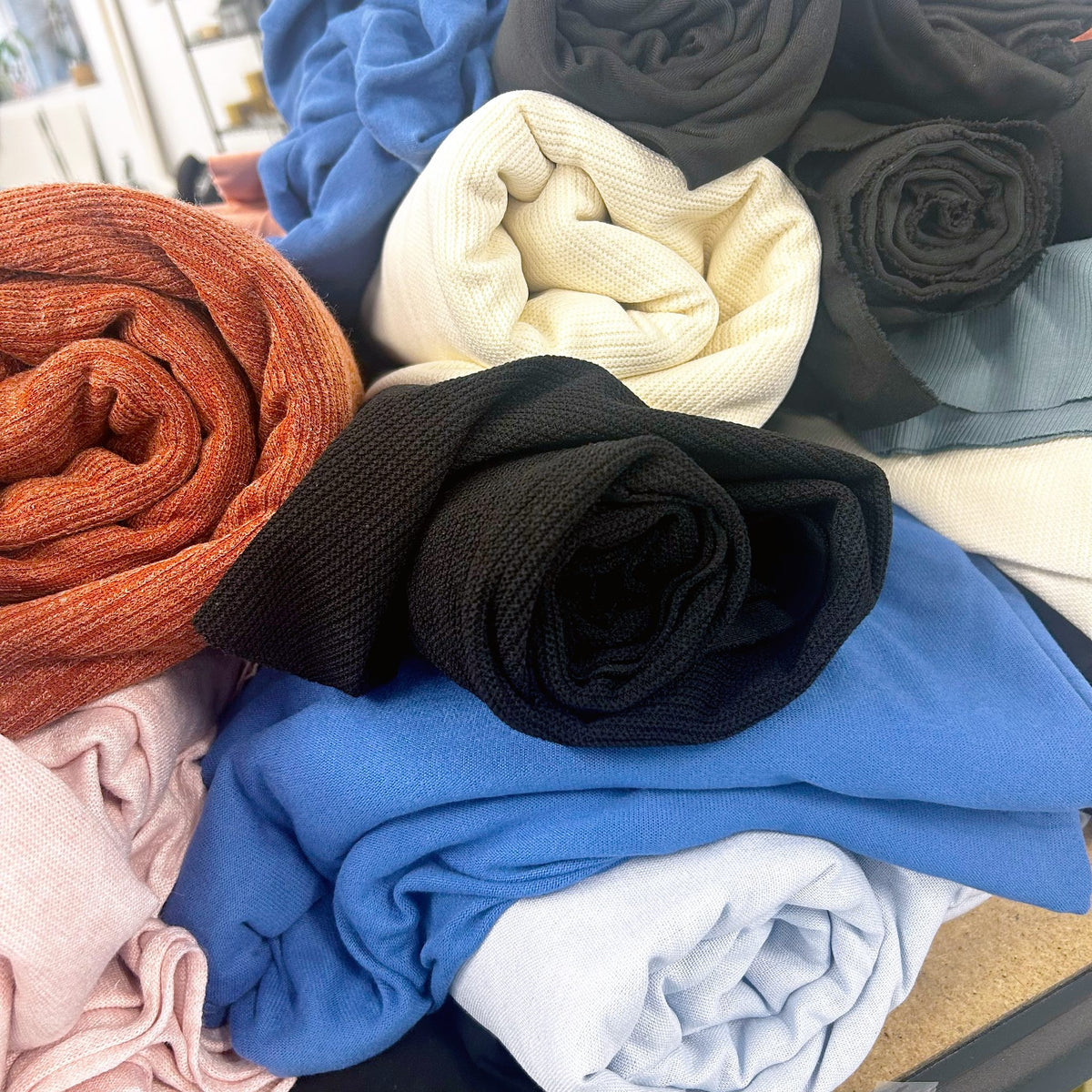Pile of assorted knit and woven fabric pieces in rust, cream, black and blue