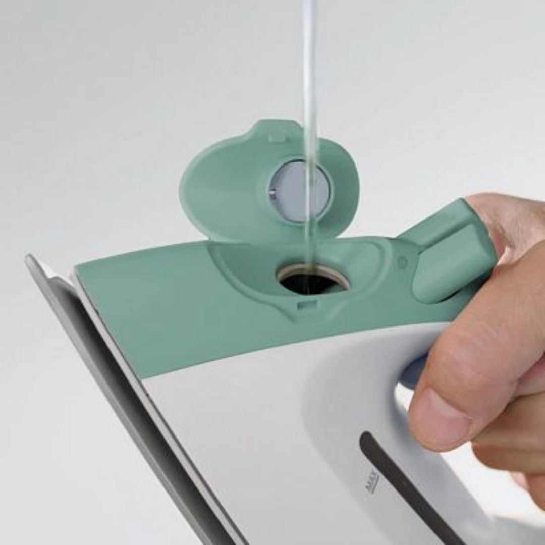 Hand filling up a  green iron with water. 