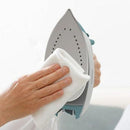 Person cleaning an iron with a white cloth on a light background