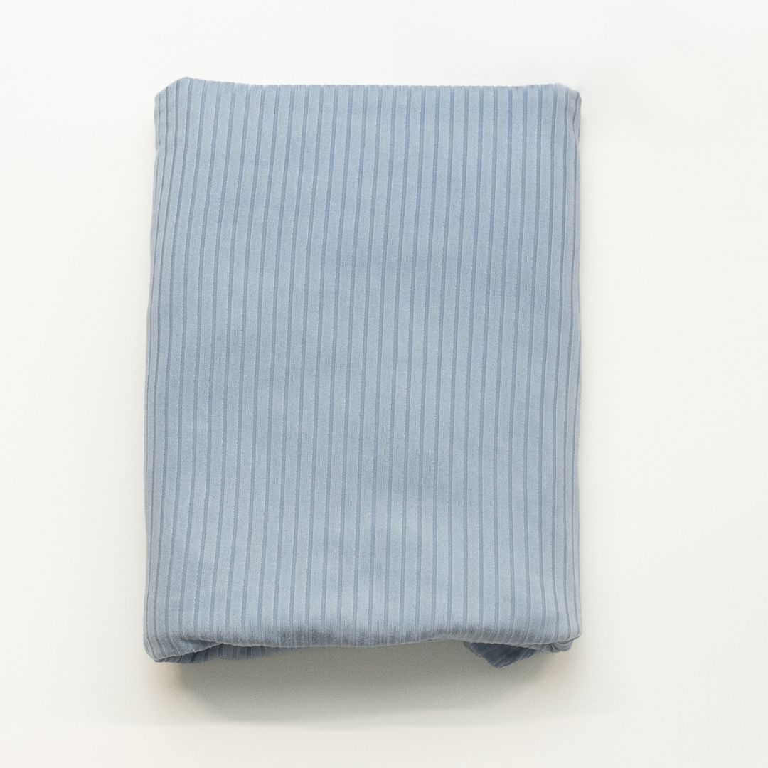 Folded light blue ribbed fabric on a white background