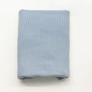 Folded light blue ribbed fabric on a white background