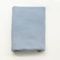 Folded light blue ribbed fabric on a white background