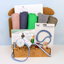 Crafting kit with fabric, tools, and instructions on a white surface