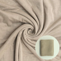 Close-up of beige fabric with a swirled pattern and inset showing a square swatch.