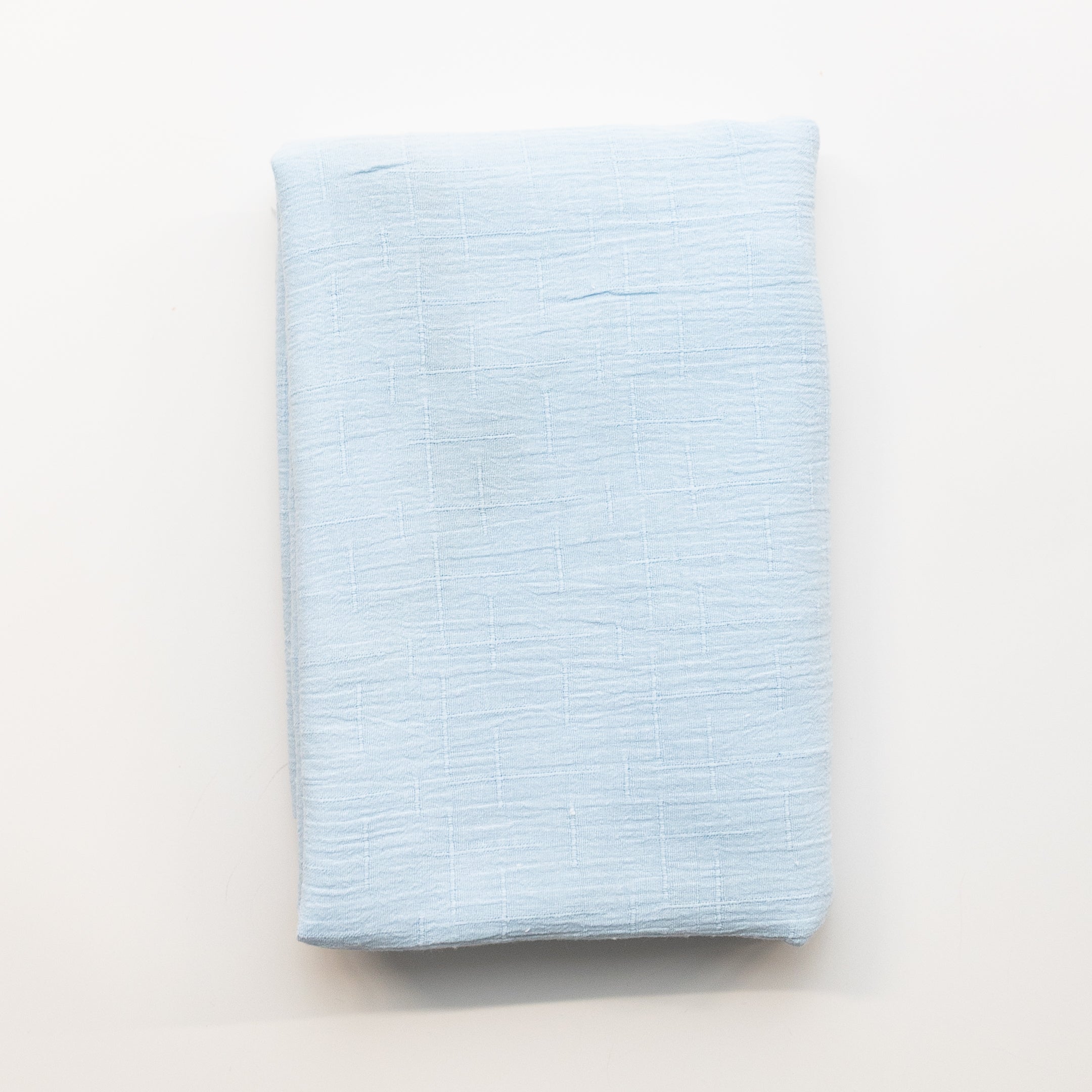 A folded piece of light pale blue fabric displayed flat against a clean white background.