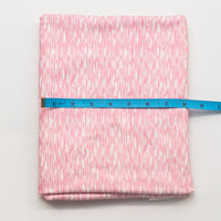 Pink fabric with a subtle pattern on a white background, measured by a blue ruler.