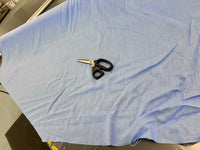 Pair of scissors on a piece of light blue fabric