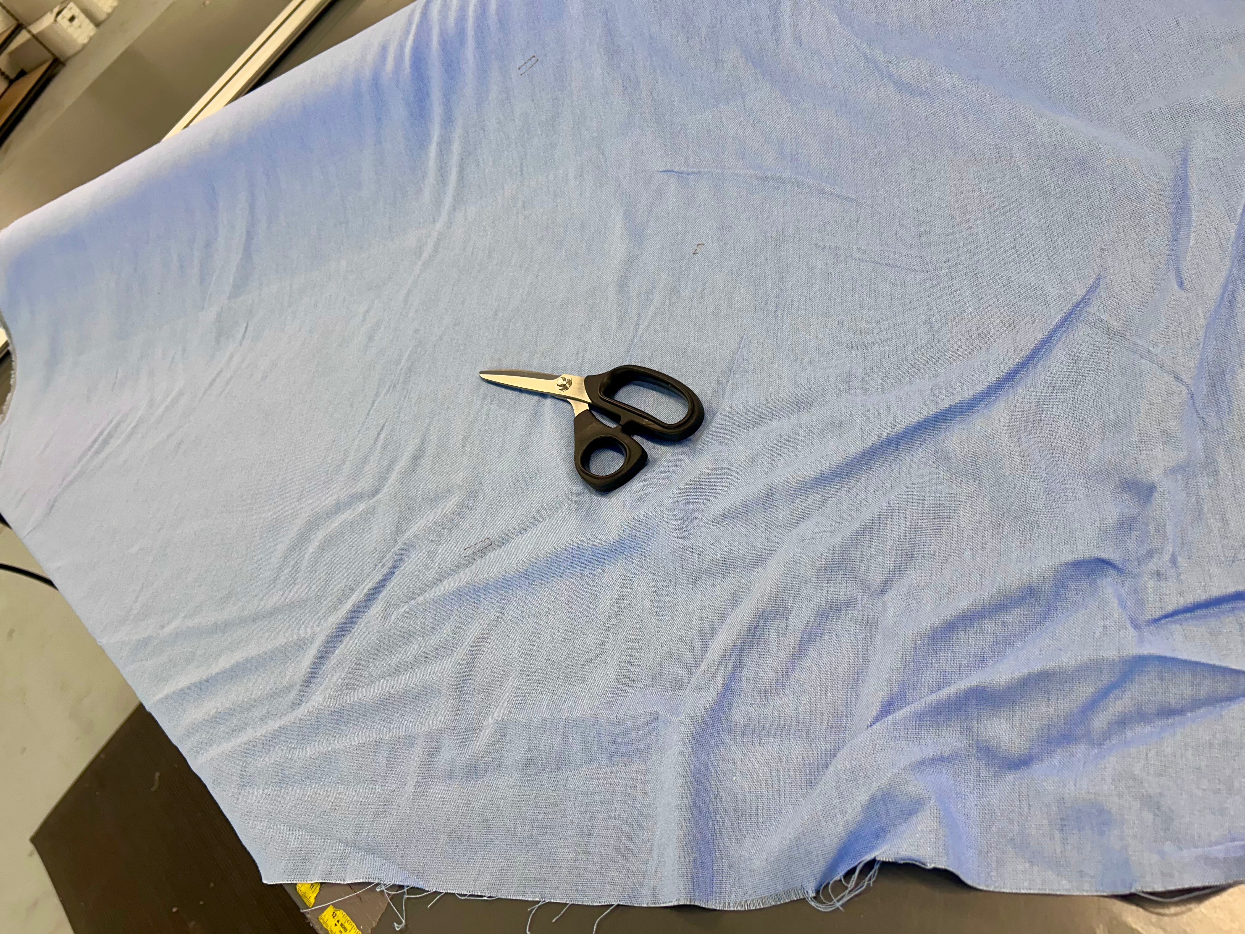 Pair of scissors on a piece of light blue fabric