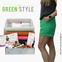 Open box of Tavi Project box displaying fabric and notions next to women modeling green pair of tavi shorts