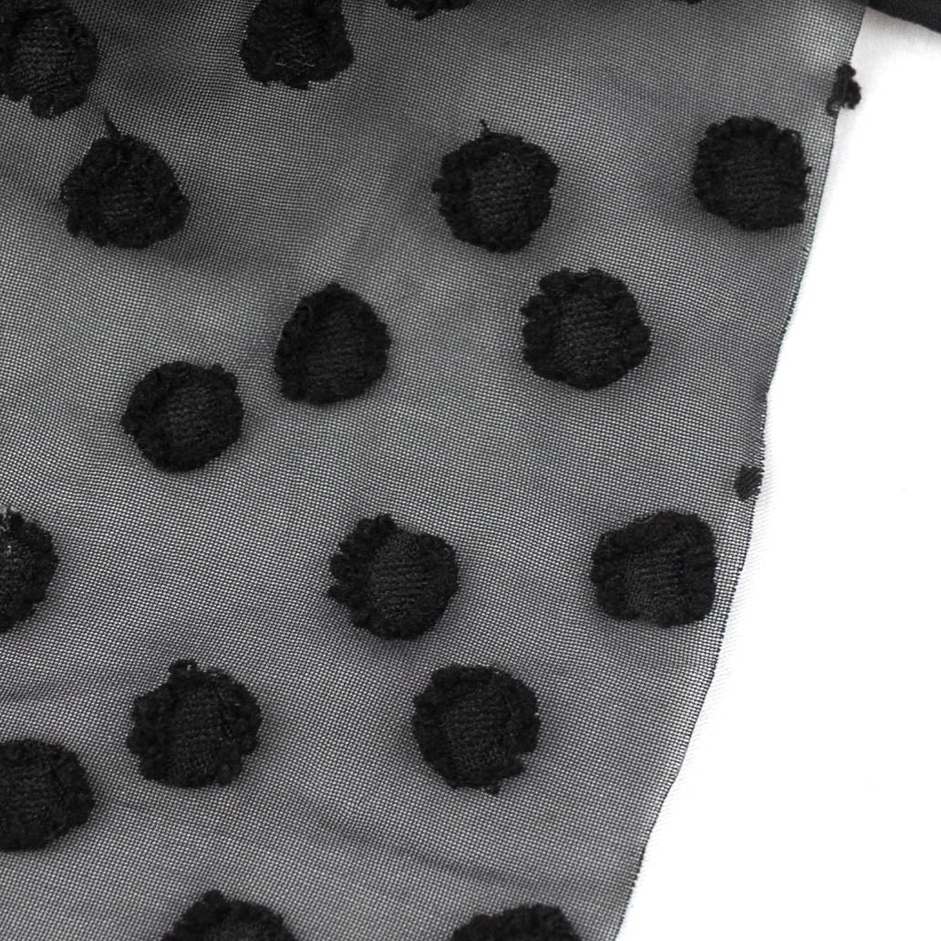 Sheer black fabric with raised black jacquard dots, shown on white