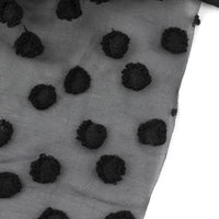 Sheer black fabric with raised black jacquard dots, shown on white