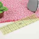 Hot ironing ruler laid on pink floral fabric next to an iron