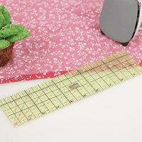 Hot ironing ruler laid on pink floral fabric next to an iron